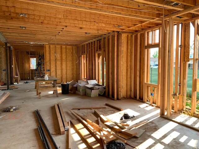Interior view of a wooden frame construction site with beams and windows.