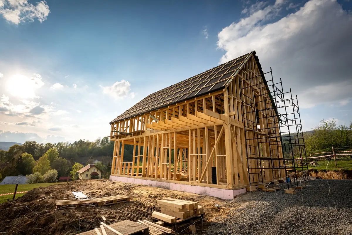 Interior view of a wooden frame construction site with beams and windows.