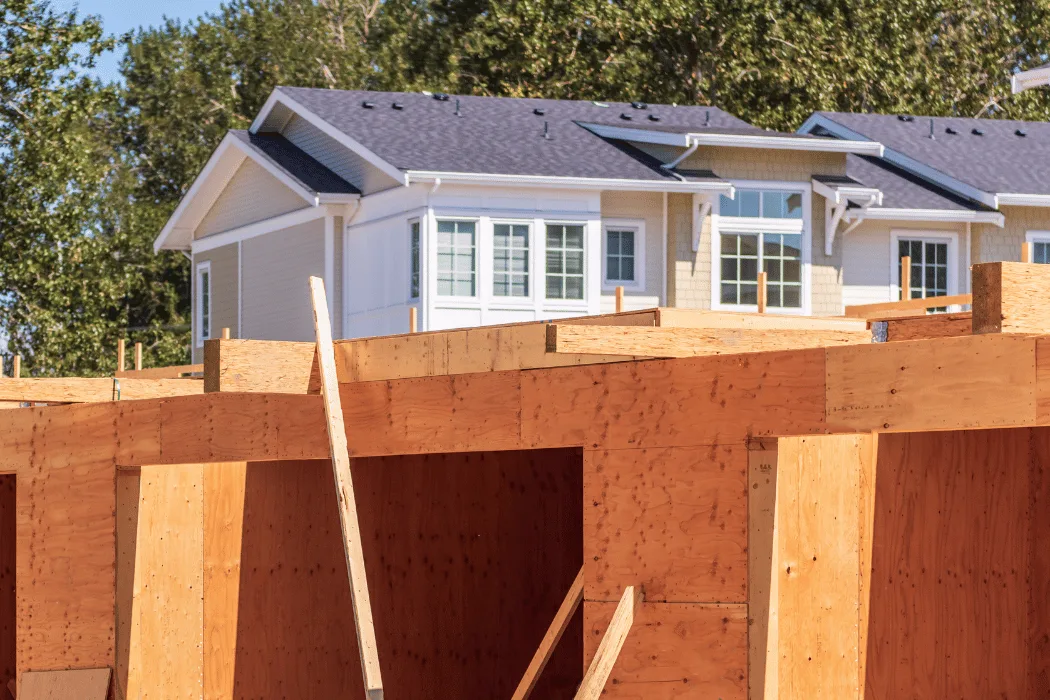 Interior view of a wooden frame construction site with beams and windows.