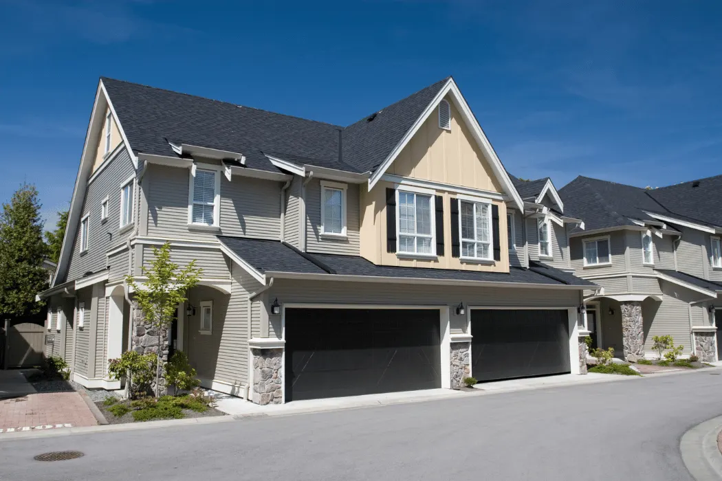 home exterior Front view of a modern stone house with a landscaped yard and two garage doors.